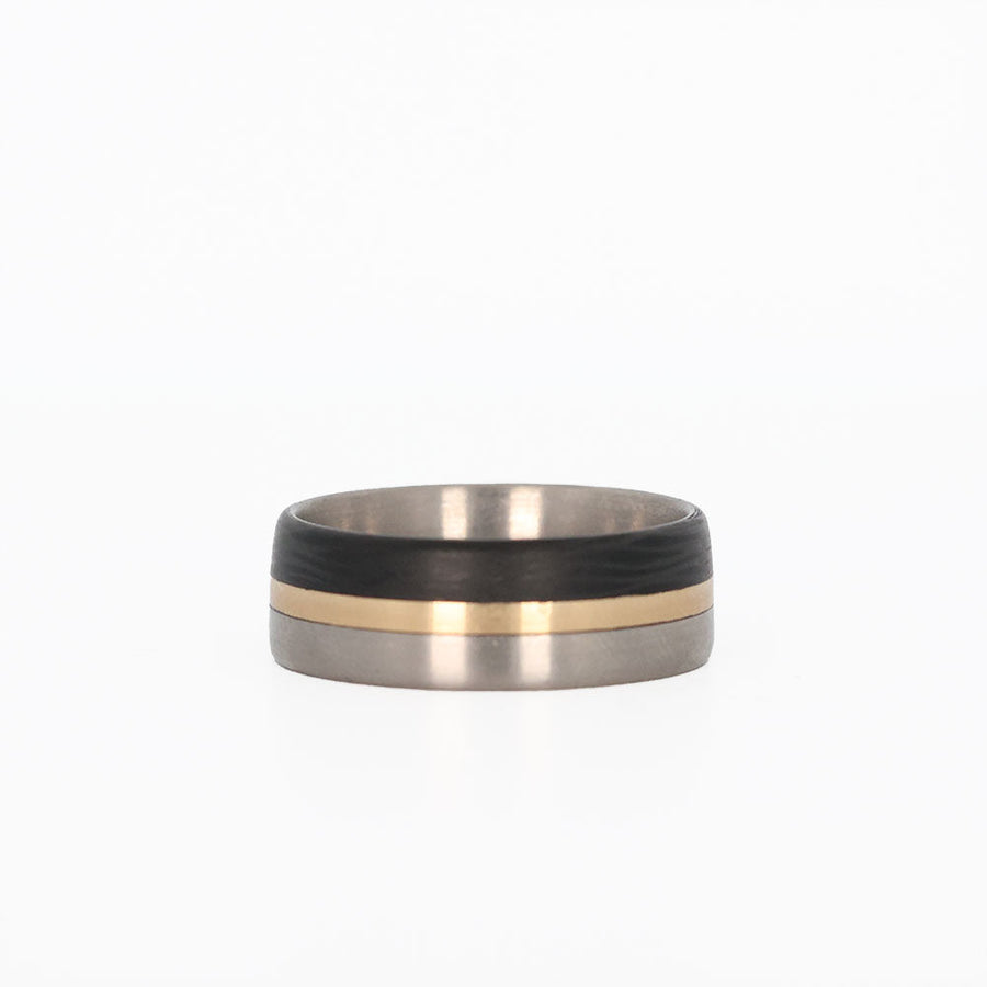titanium ring with gold and carbon fiber inlays laying flat