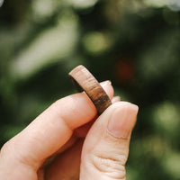 koa wood ring with carbon fiber sleeve held in fingers