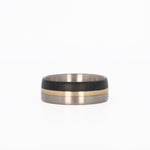 titanium ring with gold and carbon fiber inlays laying flat