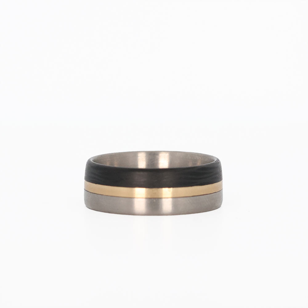 titanium ring with gold and carbon fiber inlays laying flat