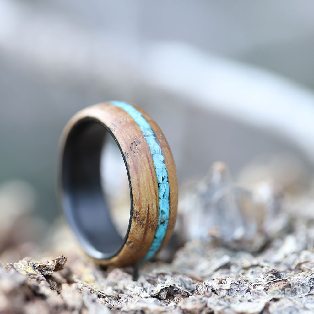 Turquoise Inlay Ring with Whiskey Barrel Wood and Carbon Fiber Sleeve On Ground