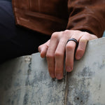 70/30 walnut wood ring with carbon fiber sleeve worn on finger
