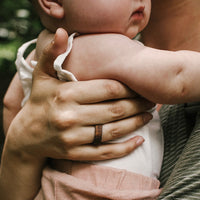 koa wood ring with carbon fiber sleeve worn while holding a baby