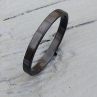 black stackable ring made from carbon fiber on painted wood