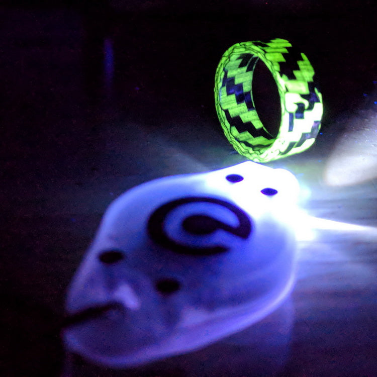 A micro uv key chain light shining on a carbon fiber ring