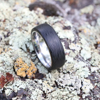 Men's Titanium Wedding Band with Carbon Fiber On A Mossy Rock