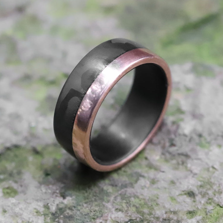 carbon fiber wedding band with rose gold rail on mossy rock