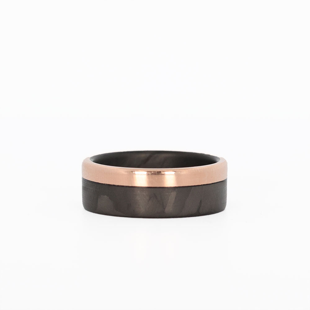 carbon fiber wedding band with rose gold rail laying flat