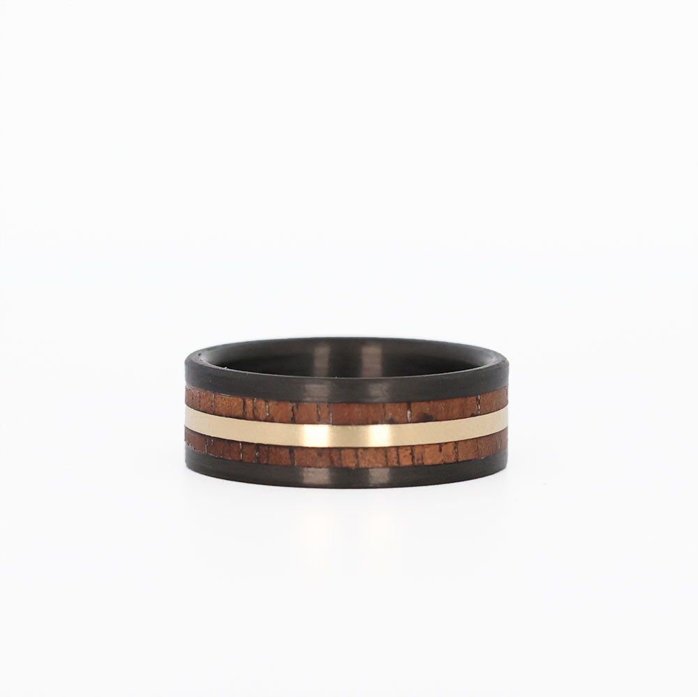 hawaiian koa wood ring with a gold inlay and carbon fiber sleeve laying flat