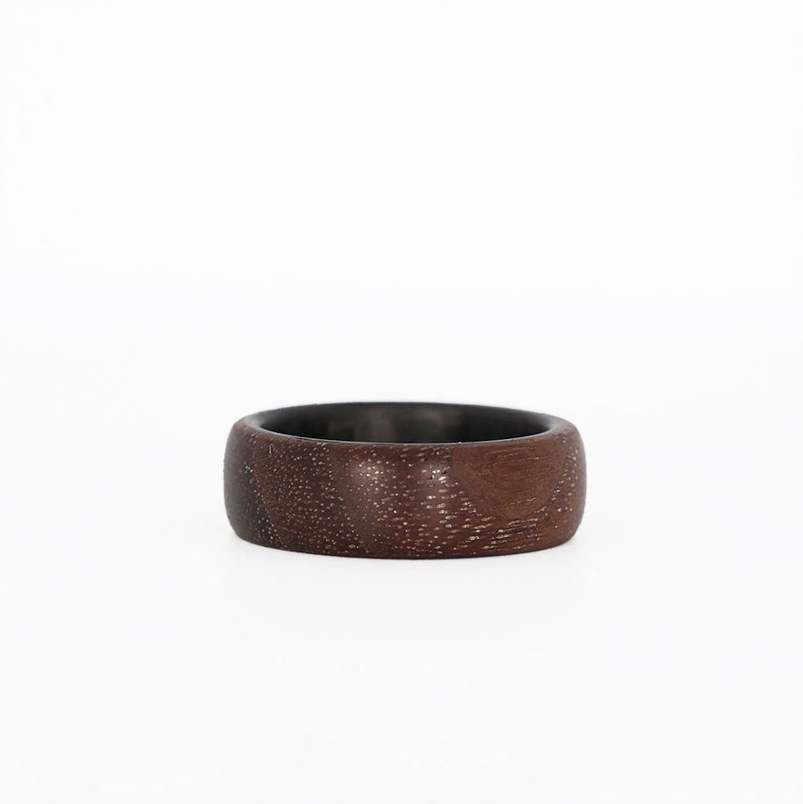 walnut wooden wedding ring with carbon fiber sleeve laying flat