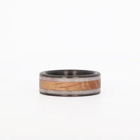 Picture of a deer antler wedding band with whiskey barrel wood and carbon fiber sleeve laying down