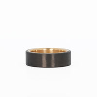men's gold wedding ring with carbon fiber laying flat